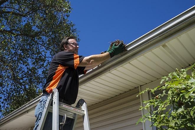 home improvement professional repairing a clogged gutter in Milton